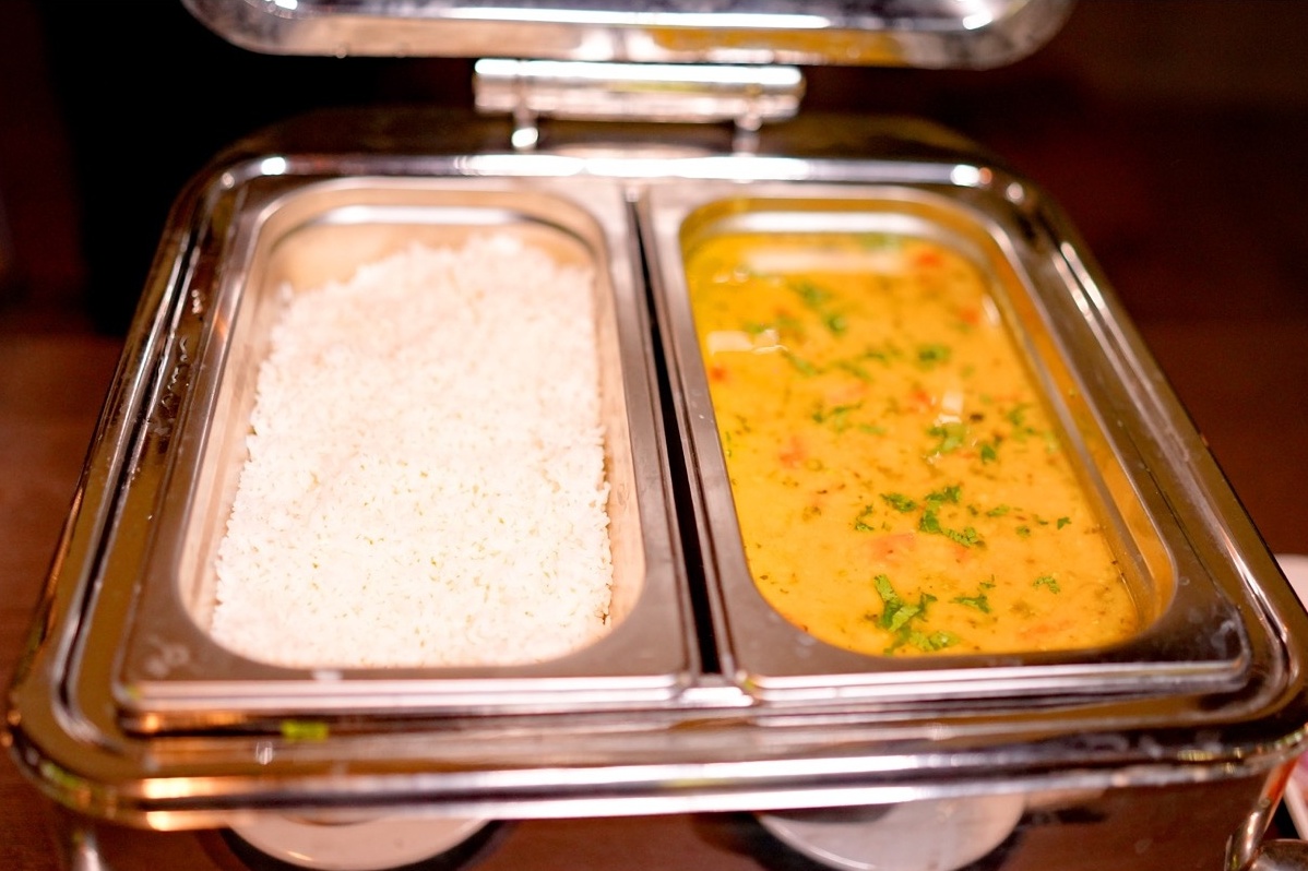 Rosewood Villas Pench buffet station with rice, dal, and accompaniments arranged in shining chafing dishes.