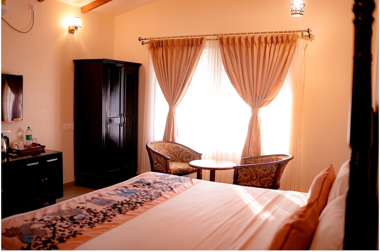 Rosewood Villas Pench bedroom seating area by window with cushions and forest view outside.