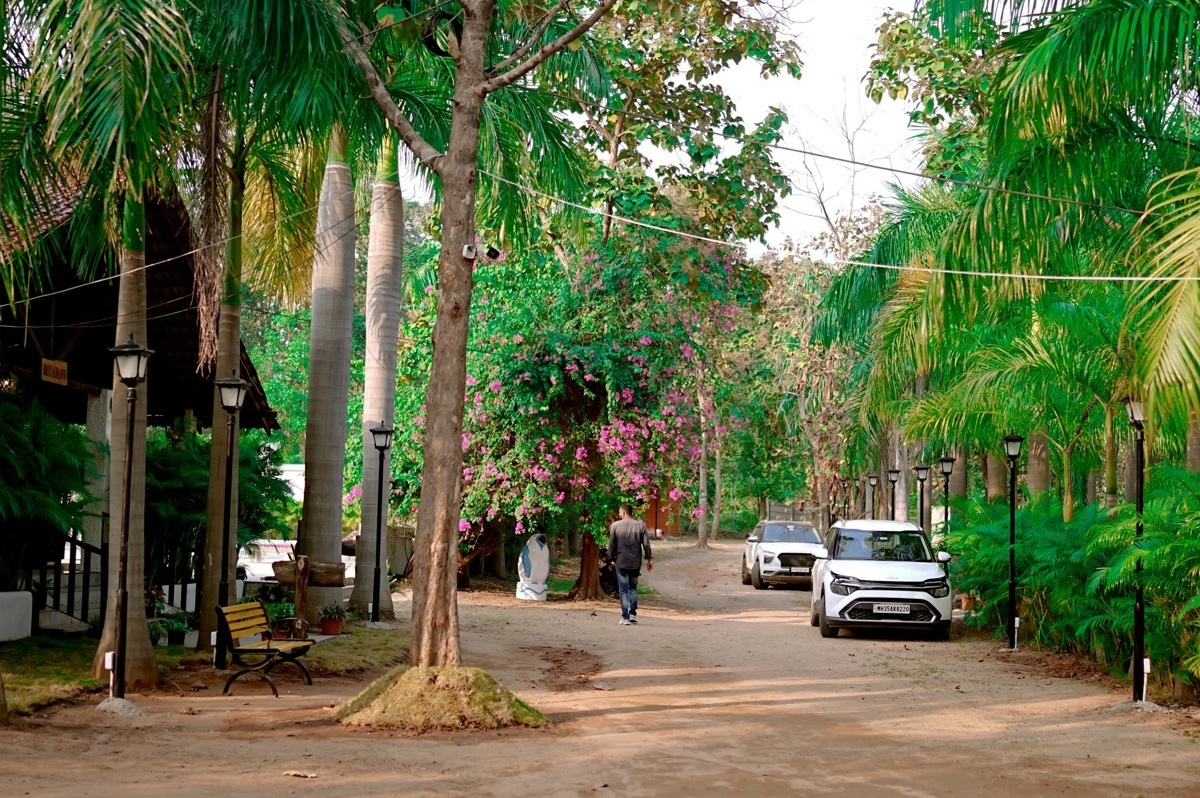 Rosewood Villas Pench garden pathway with village-style parking area and cottages around.