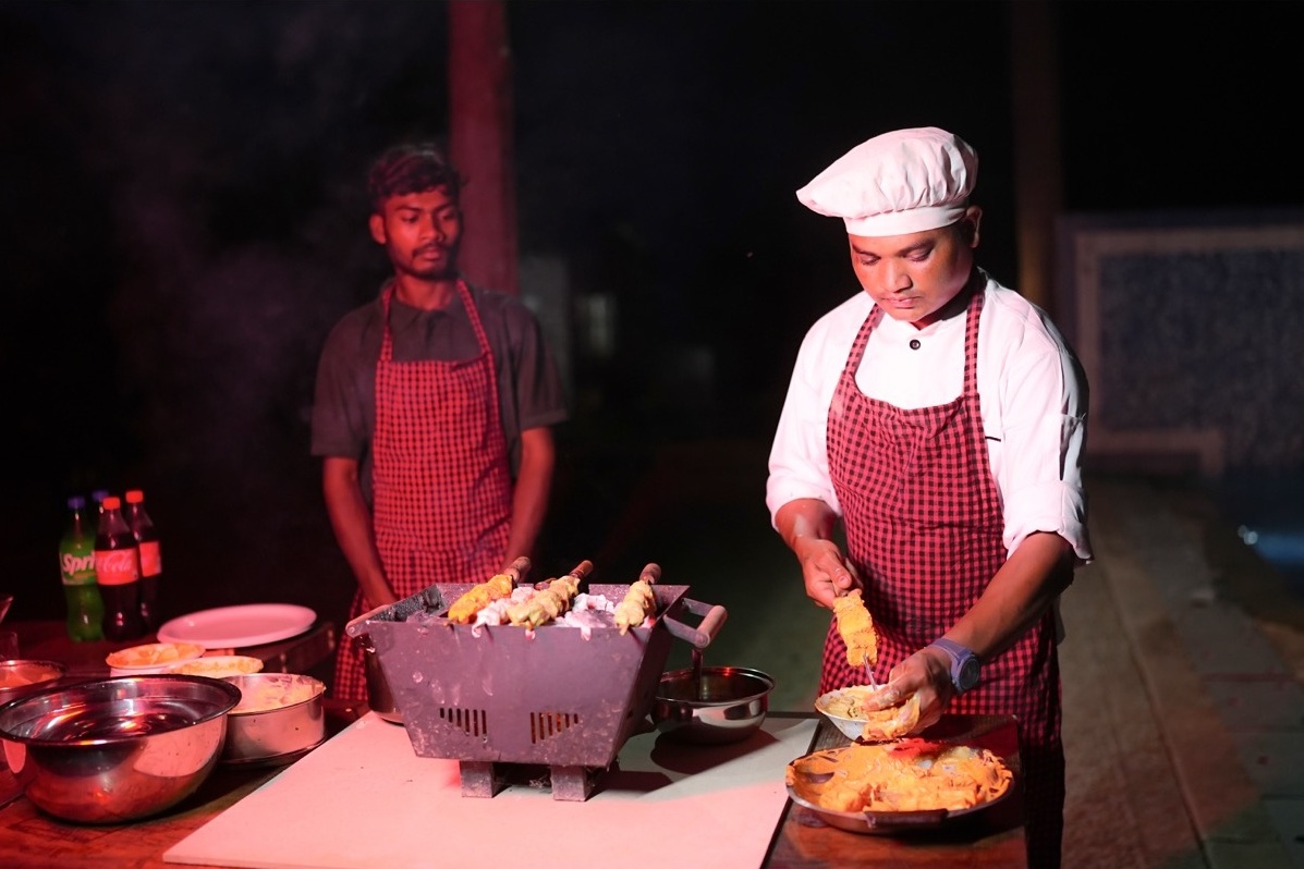 Rosewood Villas Pench chef preparing corn on a live barbecue grill station.