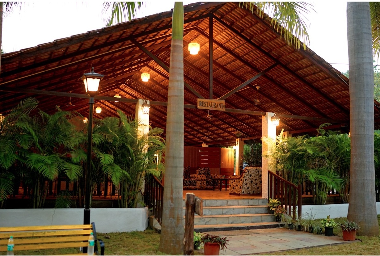 Rosewood Villas Pench restaurant entrance at evening with lanterns, wooden railings, and warm lighting.