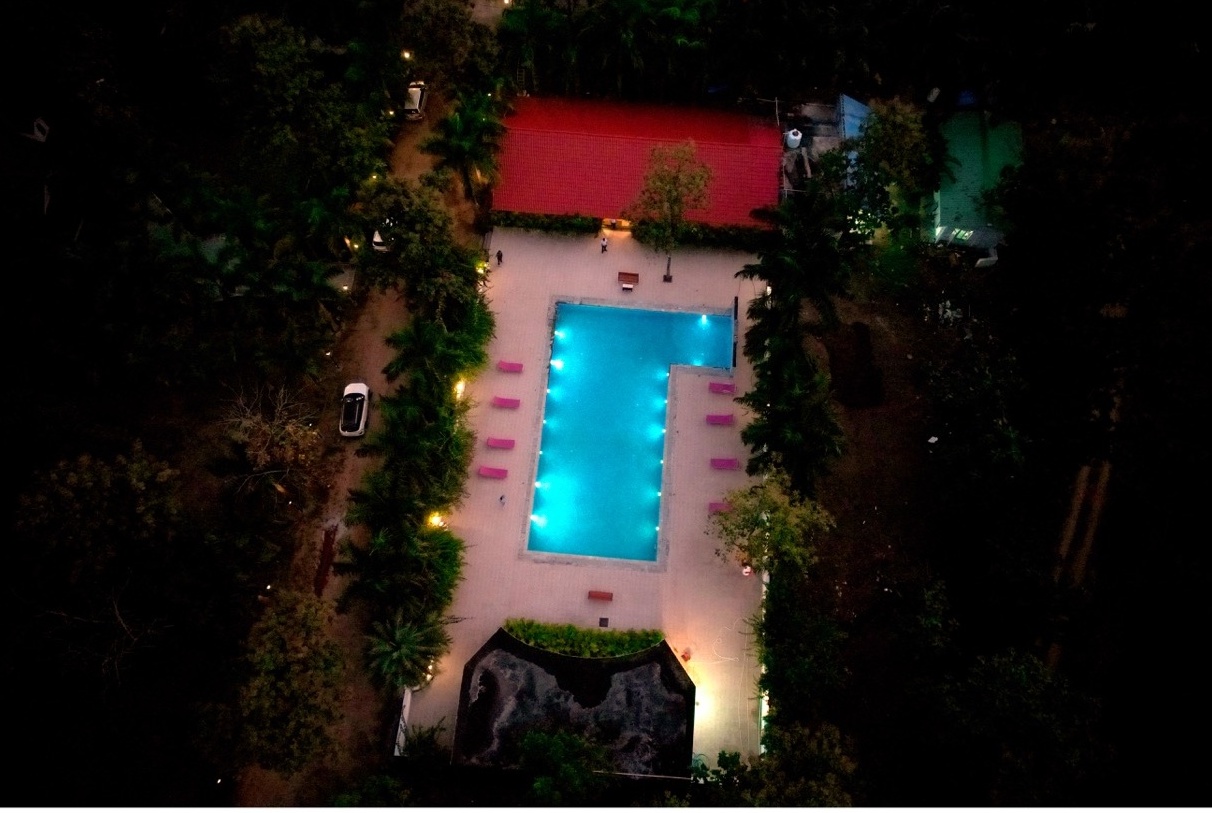 Evening aerial view of Rosewood Villas Pench swimming pool glowing against the surrounding forest.