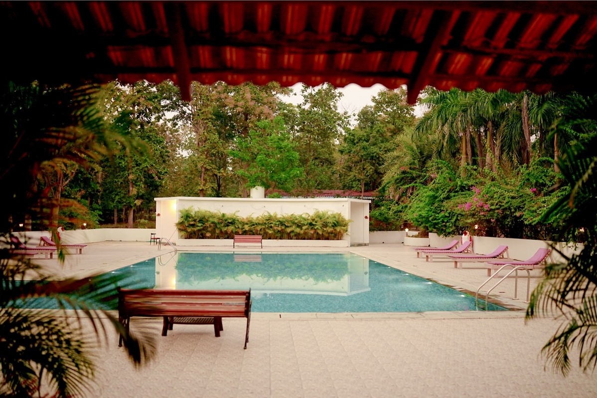 Rosewood Villas Pench swimming pool at evening with forest view in the background.